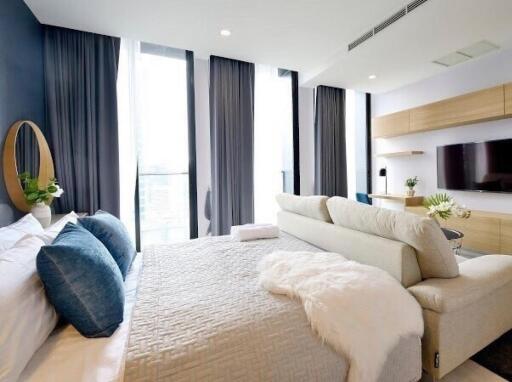 Modern bedroom with large windows, bed, couch, and TV