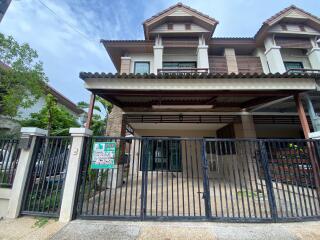 Front view of a two-story house with a gated entrance and carport