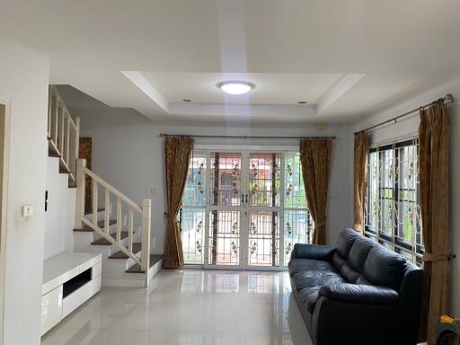 modern living room with black leather couch and staircase