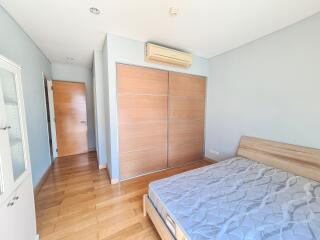 Bright and spacious bedroom with wooden flooring and large wardrobe