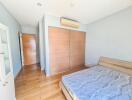 Bright and spacious bedroom with wooden flooring and large wardrobe