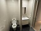 Modern bathroom with toilet, sink, mirror, and glass partition