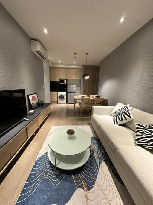 Modern living room with sofa and TV, open to dining area and kitchen