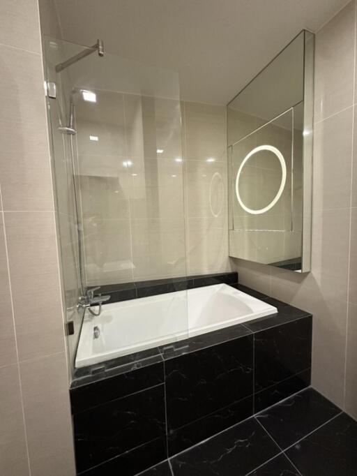 Modern bathroom with bathtub and illuminated mirror