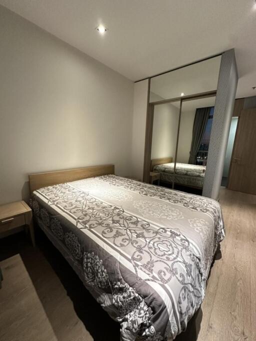 Modern bedroom with a full-size bed, bedside table, and mirrored wardrobe