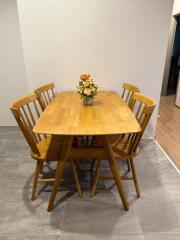 Wooden dining table with four chairs and a flower vase centerpiece