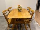 Wooden dining table with four chairs and a flower vase centerpiece