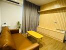 Modern living room with a brown leather sofa, wooden coffee table, air conditioning unit, and wall-mounted wooden paneling.