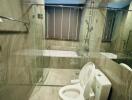 Modern bathroom with sleek gray tiles, bathtub, toilet, and glass shower enclosure