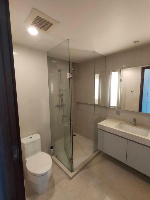 Modern bathroom with glass shower, toilet, and vanity