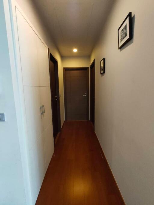 well-lit hallway with wooden flooring and wall art