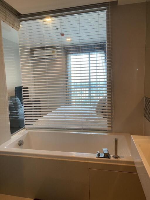 Bathroom with bathtub and view to bedroom through blinds