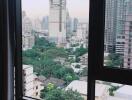 View from the window of a high-rise building showing a cityscape with construction and greenery