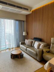 Modern living room with sofa, armchair, coffee table, and floor-to-ceiling window with blinds