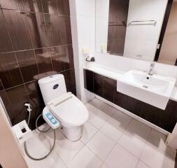 Modern bathroom with toilet, sink, and large mirror