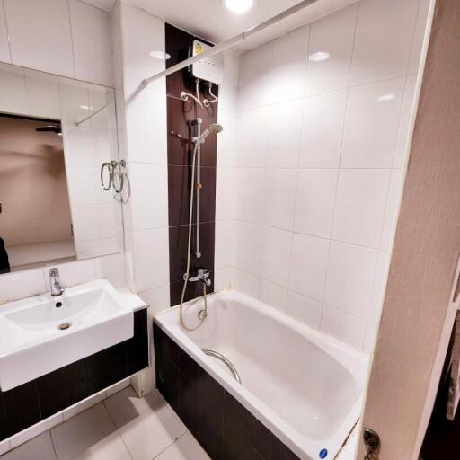 Modern bathroom with white tiles, bathtub, and sink with mirror