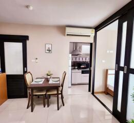 Modern, well-lit living area featuring a dining table, chairs, kitchen space, and sliding glass doors