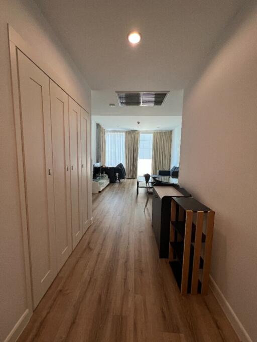 A corridor leading to a living area with wooden flooring and modern furnishings