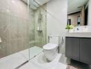 Modern bathroom with glass-enclosed shower, toilet, and vanity