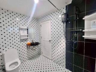 Modern bathroom with black and white tile design, shower, and toilet