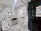 Modern bathroom with black and white tile design, shower, and toilet