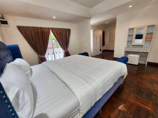 Spacious bedroom with large bed, wooden floor, and vanity table