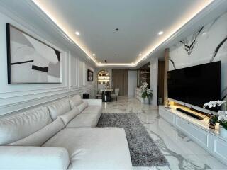 Modern living room with white sofa, large TV, and stylish decor