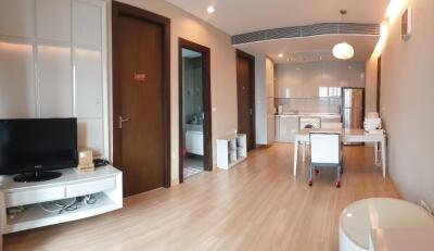 Living area with open kitchen, dining table, and wooden flooring