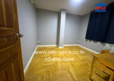 Empty bedroom with parquet flooring and small table