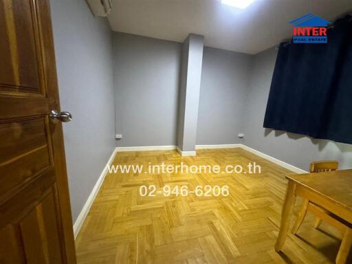 Empty bedroom with parquet flooring and small table