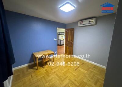 Empty room with wooden floor, small wooden table, and blue-gray walls