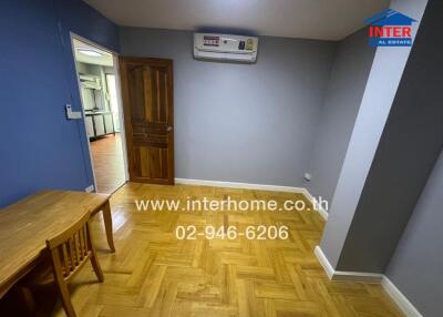 Room with wooden floor, small wooden table and chair, and view of adjacent kitchen