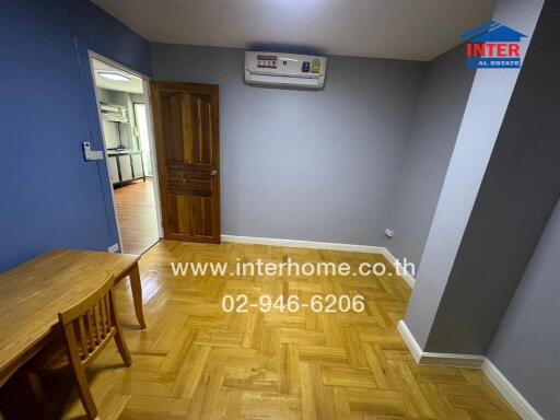 Room with wooden floor, small wooden table and chair, and view of adjacent kitchen