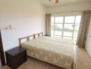 Bedroom with bed, side table, ceiling fan, and window with curtains