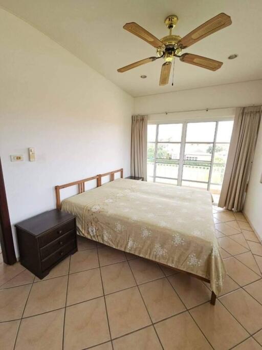 Bedroom with bed, side table, ceiling fan, and window with curtains