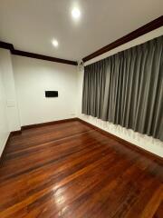 Empty bedroom with wooden flooring and curtains