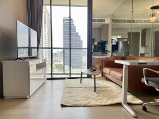 Modern living room with city view, leather sofa, TV, and desk area