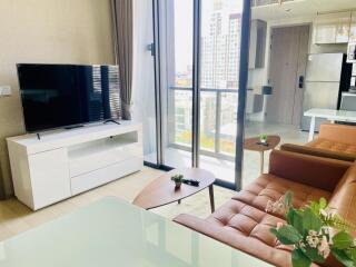 Modern living room with a TV, sofa, coffee table, and large windows