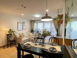 Living room with dining area featuring a cozy couch, dining table, and large windows