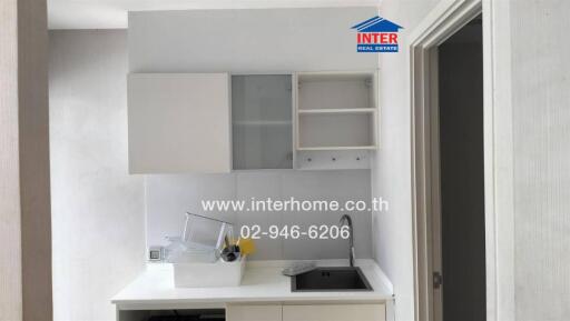 Small kitchen area with white cabinetry and sink