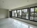 Spacious living room with large windows and tiled floor