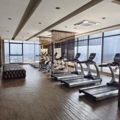 Modern gym with treadmills, exercise bikes, and large windows