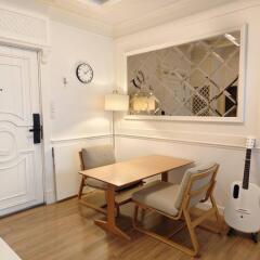 Compact dining area with a wooden table, two chairs, a decorative wall mirror, and a guitar