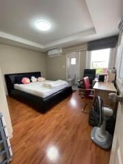 Modern bedroom with wooden flooring, a large bed, and an ensuite bathroom