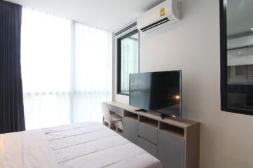 Modern bedroom with large window, television and air conditioning