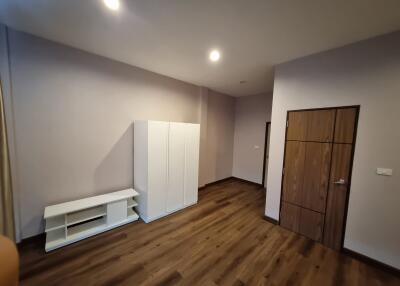 Spacious bedroom with wooden flooring and white furniture