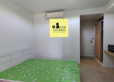 Well-lit bedroom with green bedspread and air conditioning