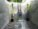 Outdoor shower area with stone flooring and potted plants