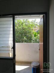 View from doorway looking out onto a balcony with greenery in the background