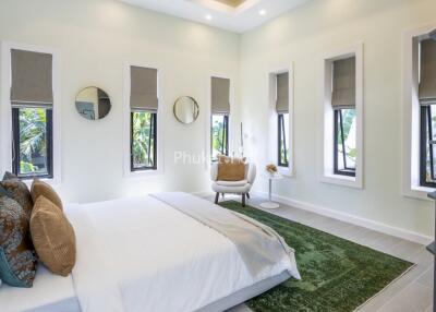 Bright and spacious modern bedroom with large windows and a green rug